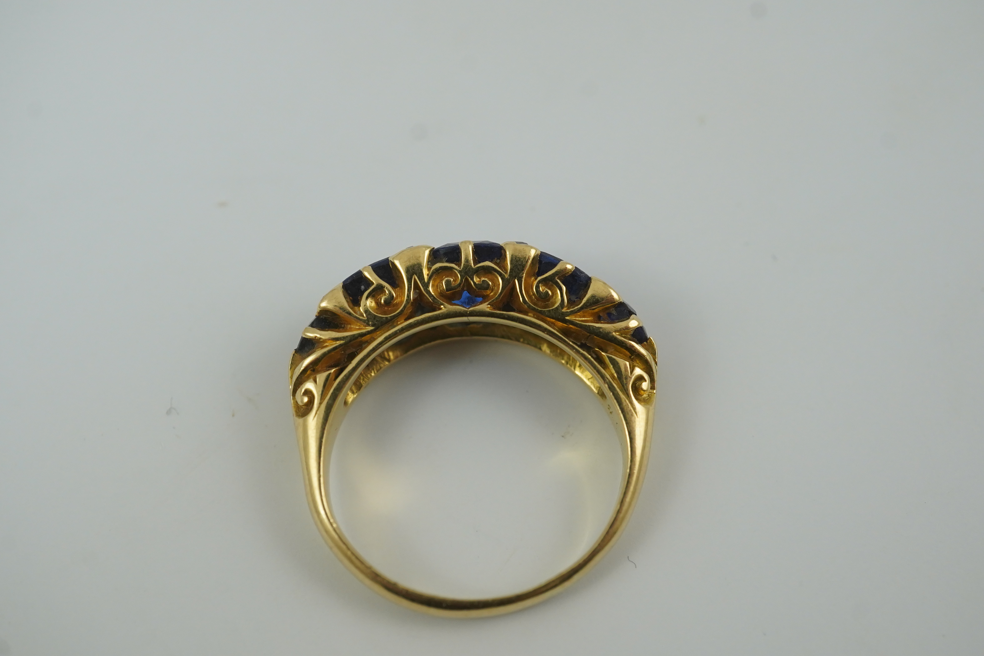 A late Victorian 18ct gold and graduated five stone blue doublet set half hoop ring